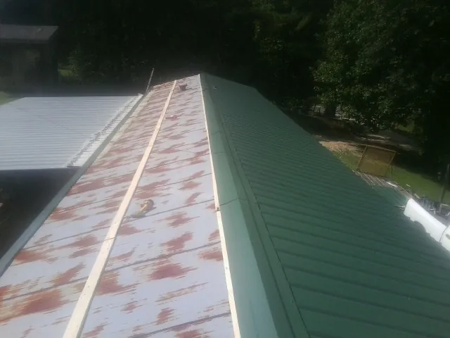 Old rusted panels beside newly installed green metal roofing — Wind Damage Roof Repair by Roofing Brothers in Happy Valley