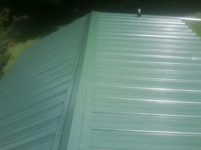 New green metal panels meeting at the ridge of a roof — Flat Roof Repair work by our crew in Happy Valley