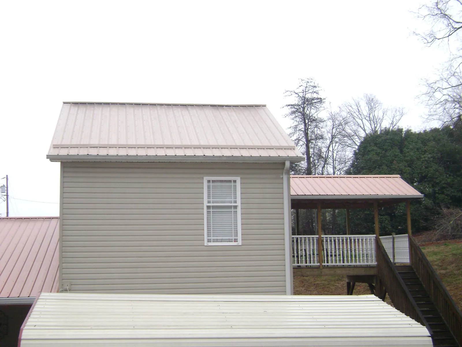 Tan metal roofs on a two story addition and attached porch, from a Roof Replacement job in Happy Valley