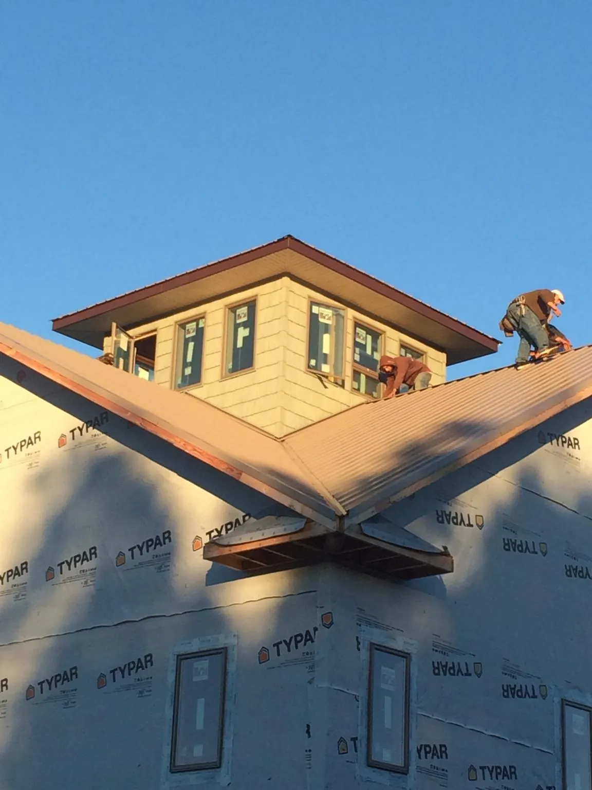 Roofers working around a rooftop cupola on a new metal roof at sunset — Roof Waterproofing in Happy Valley by Roofing Brothers